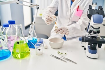 Fototapeta premium Young chinese woman wearing scientist uniform using syrup bottle at laboratory