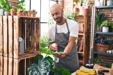 Young bald man florist using difusser working at florist