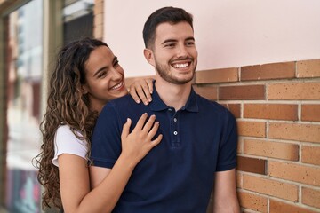 Young hispanic couple smiling confident hugging each other at street