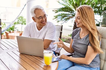 Middle age hispanic couple using laptop at the terrace.