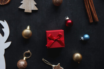 Small presents, various Christmas ornaments and deer figurine on dark background. Top view.
