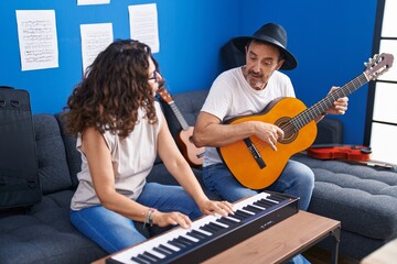 Man and woman musicians playing piano and classical guitar at music studio