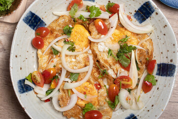 Spicy fried egg salad with vegetables, tomatoes, onions