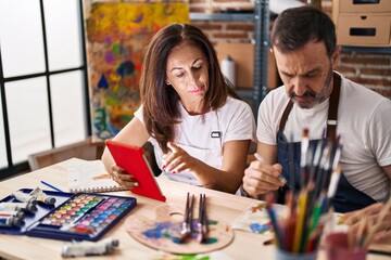 Fototapeta premium Middle age man and woman artists drawing on notebook using touchpad at art studio