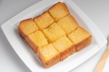 Toasted bread slices topped with sweetened condensed milk in a white plate.
