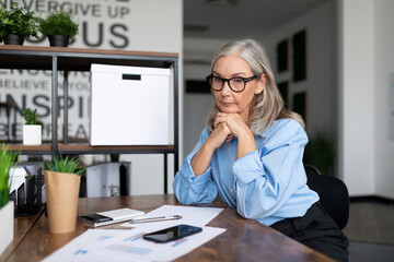 adult mature business woman sitting at the office desk at work looking at documents. Accounting Bookkeeper Clerk Woman concept