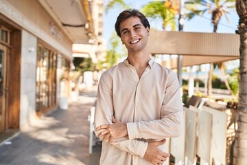 Young caucasian man standing with arms crossed gesture at coffee shop terrace