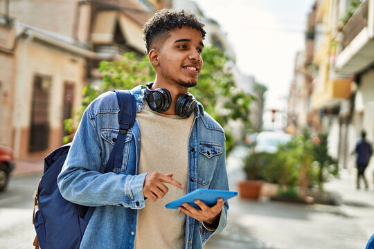 Hispanic young man using touchpad device at the street