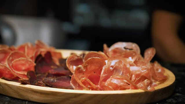 meat appetizer. food serving process. prosciutto ham and jamon cut on slicer for wine snack in meat restaurant. Appetizing slices of Iberian ham on a wooden platter