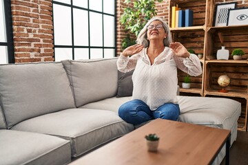 Middle age woman sitting on sofa suffering for back pain at home
