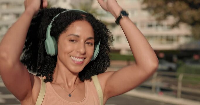 Black woman, headphones and listening to music in the city for happy dance, travel and fun in the outdoors. African American female enjoying audio dancing, good vibes and chilling in a urban town