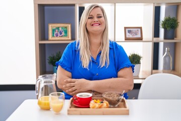 Obraz na płótnie Canvas Caucasian plus size woman eating breakfast at home happy face smiling with crossed arms looking at the camera. positive person.