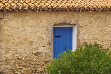 Fototapeta na wymiar House in village in rural France featuring blue door and terra cotta roof tiles