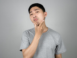 Asian man grey shirt feels worried about skin of his face isolated