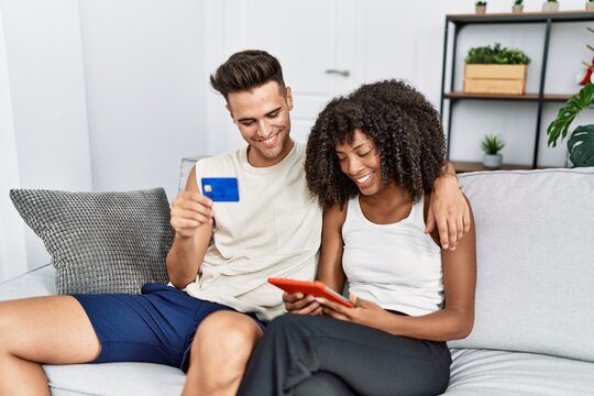 Man and woman couple using touchpad and credit card hugging each other at home