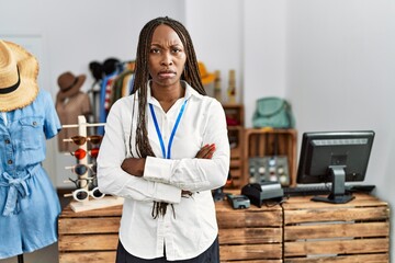 Black woman with braids working as manager at retail boutique skeptic and nervous, disapproving...