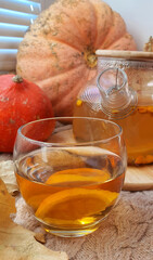 composition of pumpkin leaves and a glass teapot with tea on the window