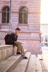 Concentrated teenager perusing a textbook outdoors