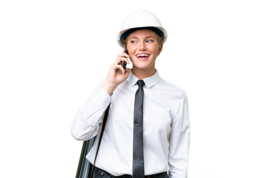 Young architect caucasian woman with helmet and holding blueprints over isolated background keeping a conversation with the mobile phone