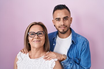 Hispanic mother and son standing together smiling with a happy and cool smile on face. showing...