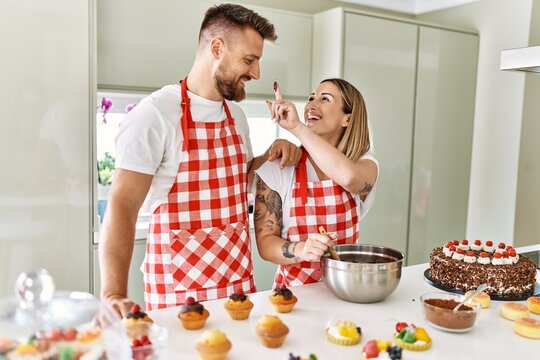 Young couple smiling confident cooking chocolate cake at kitchen