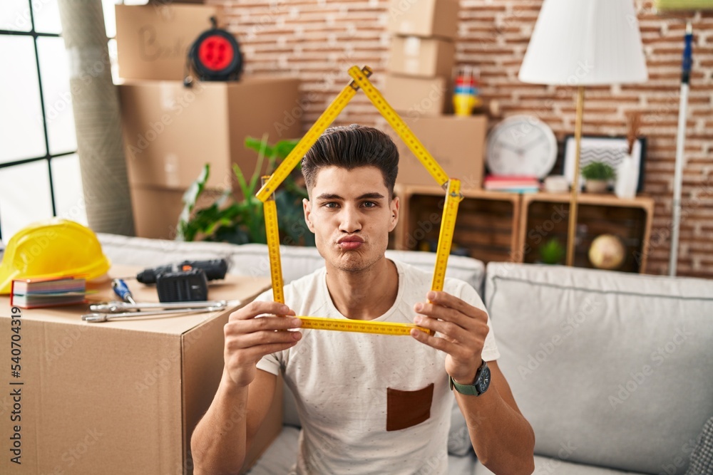 Poster Young hispanic man moving to a new home looking at the camera blowing a kiss being lovely and sexy. love expression.