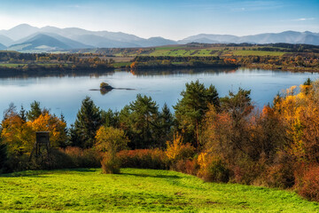 Colorful autumn landscape with lake, yellow trees and mountains at background