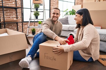 Man and woman couple packing fragile cardboard box at new home