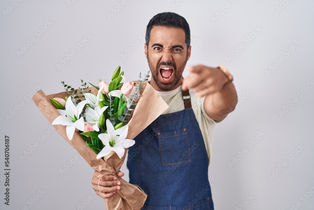 Sticker Hispanic man with beard working as florist pointing displeased and frustrated to the camera, angry and furious with you