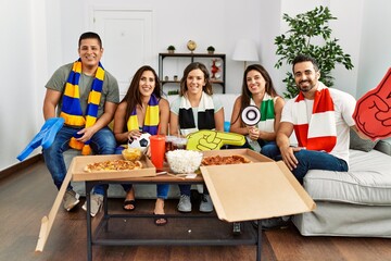 Group of young people wearing team scarf cheering football game looking positive and happy standing and smiling with a confident smile showing teeth