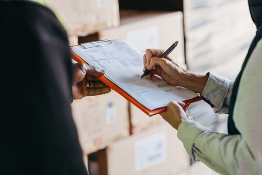 Warehouse manager signing a bill of lading on a clipboard