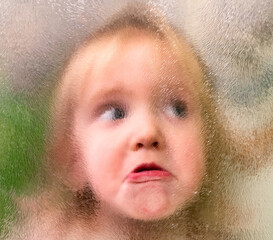 Funny baby face through blurred glass
