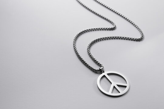 Metal medallion, with a pendant in the form of a symbol of peace on a white background.