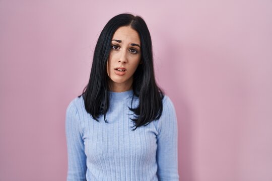 Hispanic woman standing over pink background looking sleepy and tired, exhausted for fatigue and hangover, lazy eyes in the morning.