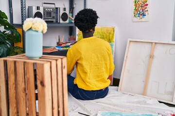 Young african american woman artist drawing sitting on floor at art studio