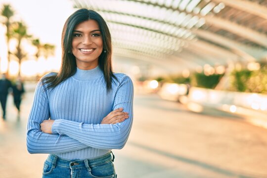 Beautiful hispanic woman smiling confient with crossed arms at the city