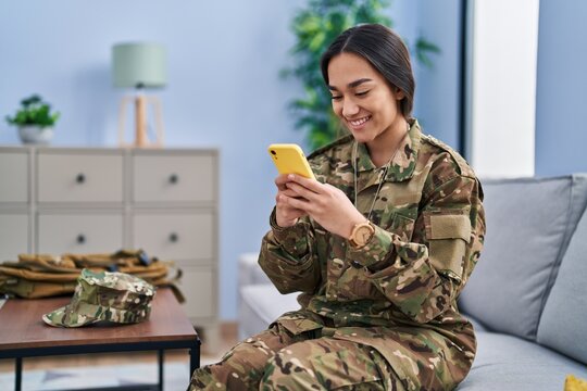 Young hispanic woman army soldier using smartphone at home - Powered by Adobe