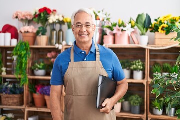 Middle age grey-haired man florist smiling confident holding binder at florist