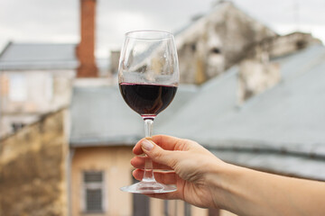 A glass of wine in a woman's hand against the background of the city