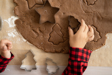little kid girl in red pajama cooking festive gingerbread in christmas decorated kitchen. christmas cookies