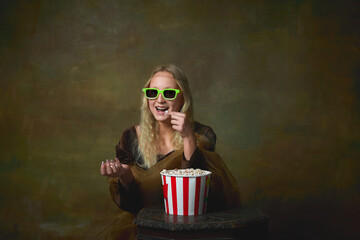 Cheerful young girl in image of Mona Lisa in 3d eyewear wathich movie over dark vintage background. Retro style, art, fashion, comparison of eras concept.