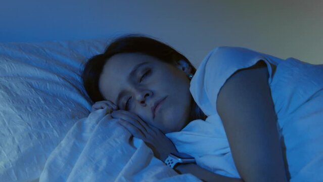 Beautiful girl sleeping cozily on a bed in her night room with Blue Colors from the moon.