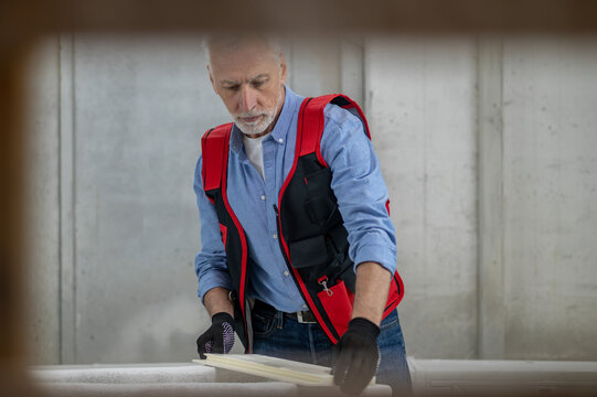 Craft Man In Red Vest With A Piece Of Wood For Painting