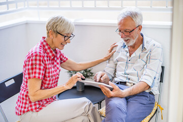 Senior couple sitting and talking on terrace at their home. Leisure time.