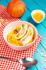 Rice milk pumpkin porridge with walnuts, butter and honey on blue wooden table. Healthy food.