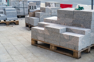 Many stacks of granite paving slabs on pallets for paving sidewalks located on a construction site...