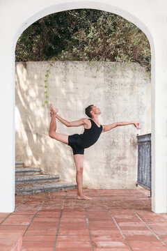 Man practicing dance pose seen through arch in front of wall