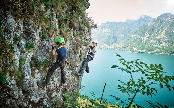 Girl with brother climbing mountain with Lake Idro in background