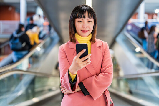 Smiling Young Woman Surfing The Net On Escalator