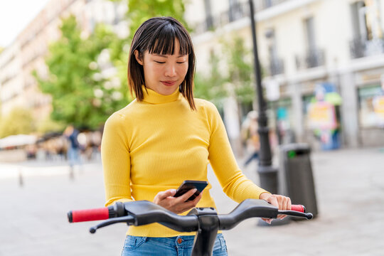 Young woman unlocking electric bike through smart phone